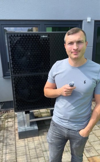 Mann in hellblauem T-Shirt vor einer großen Wärmepumpe