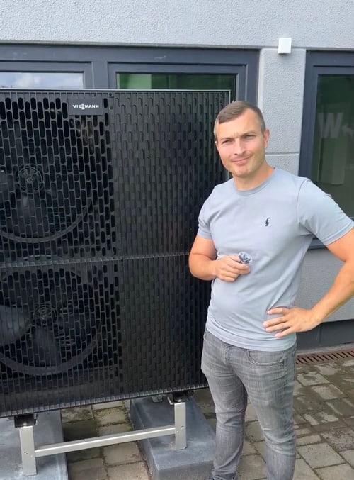 Mann in hellblauem T-Shirt vor einer großen Wärmepumpe